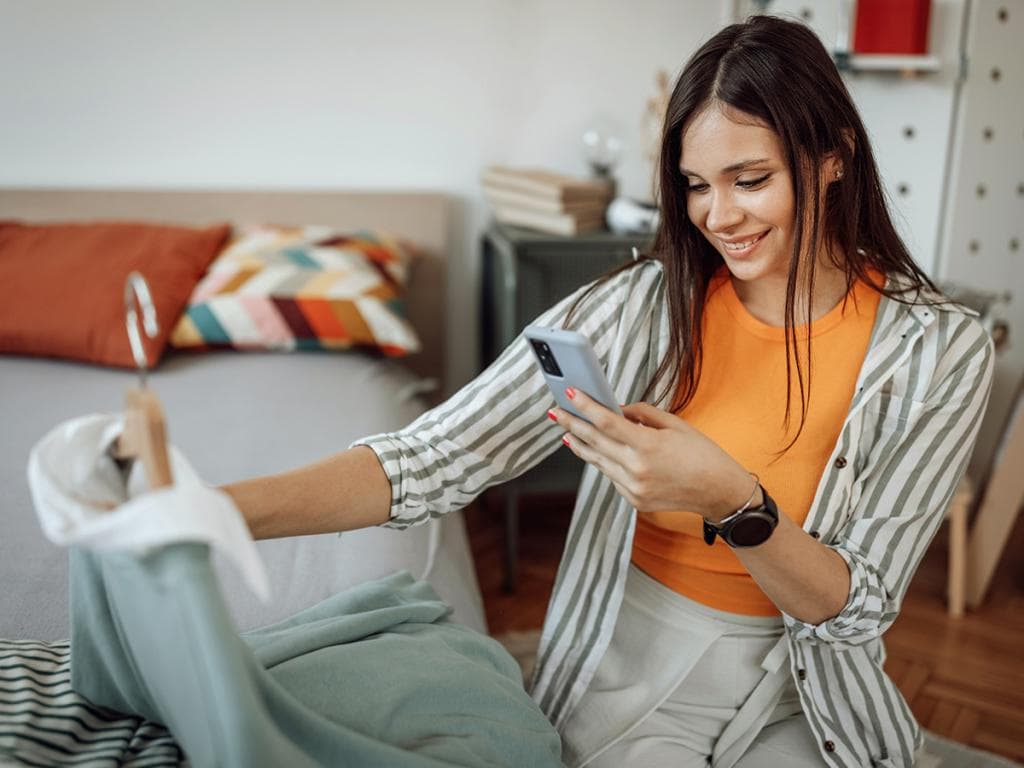 O femeie ține un smartphone și privește cu atenție ecranul