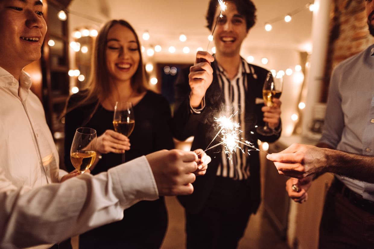 Un grup de persoane țin cu bucurie artificii și sorb vin, sărbătorind împreună într-o atmosferă festivă